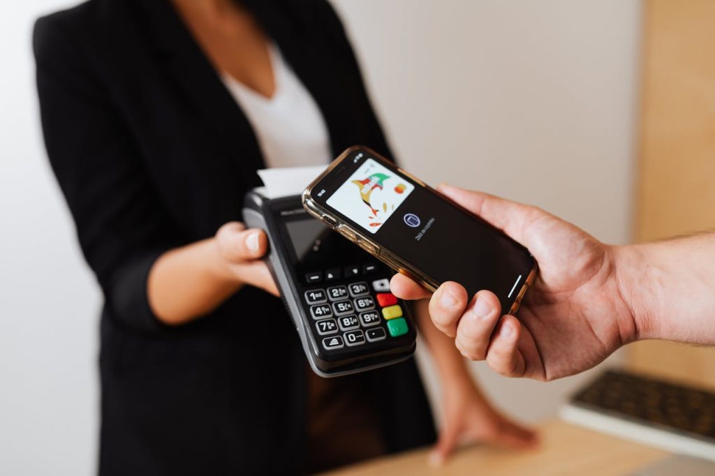 A person using a smartphone for contactless payment at a retail store counter.